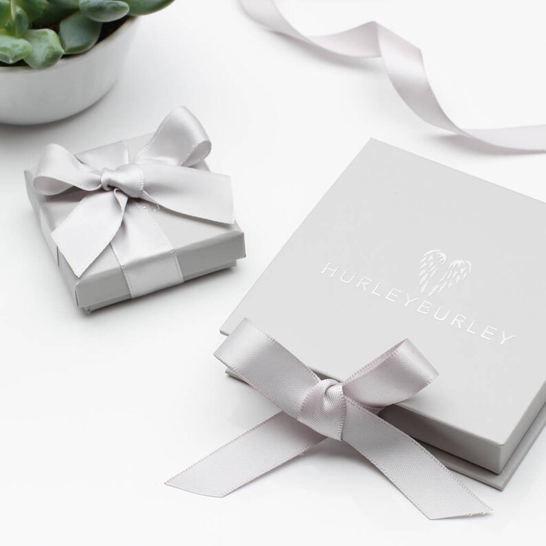 May include: Two grey gift boxes with white satin ribbon bows. The larger box has the text "HURLEYEURLEY" printed on the top.