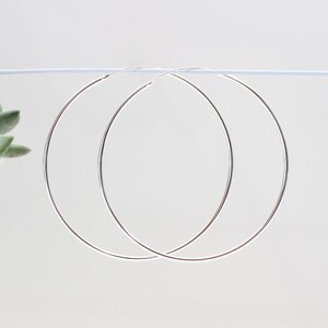 May include: A pair of silver hoop earrings. The hoops are large and circular.