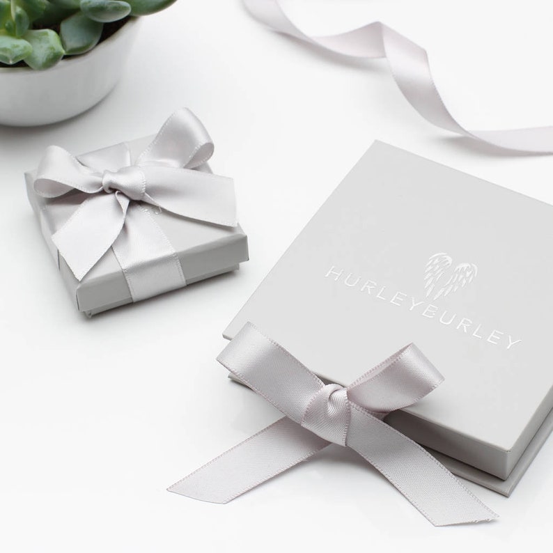 May include: Two gray gift boxes with white satin ribbon bows. The larger box has the text "HURLEYEURLEY" printed on the top.