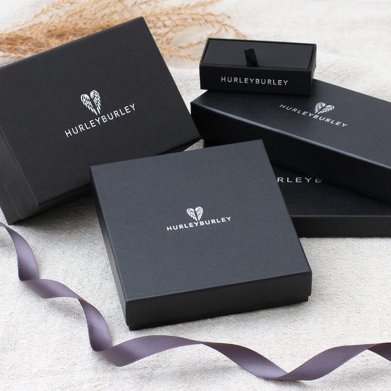 May include: Three black boxes with the Hurley Burley logo. The boxes are stacked on top of each other. The top box is smaller than the other two boxes.