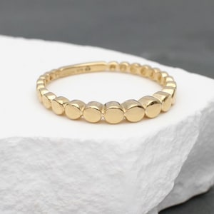 May include: A gold ring with a beaded design. The ring is made of small, round beads that are evenly spaced around the band.