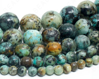 May include: A collection of turquoise gemstone beads in various shades of blue, green, and brown. The beads are round and have a smooth, polished finish.