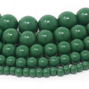 May include: A collection of green glass beads in various sizes. The beads are round and have a smooth, glossy finish.