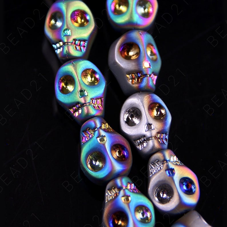 May include: A strand of iridescent skull beads with a rainbow finish. The beads are made of metal and have a detailed skull design.