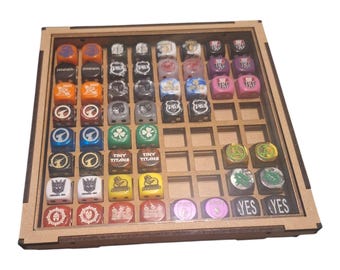 May include: A wooden dice tray with a clear acrylic cover, filled with an assortment of colorful dice and tokens. The dice feature various symbols and logos, including "Tiny Titans" and "YES" tokens. The tray is designed to hold multiple dice.