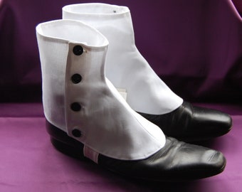 Puede incluir: Un par de polainas de bota de algodón blanco con botones negros. Las polainas se llevan sobre zapatos de cuero negro.