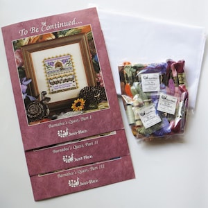 May include: A cross-stitch kit with the text "To Be Continued..." and "Barnabee's Quest" on the cover. The kit includes printed patterns, embroidery floss, and a piece of white fabric. The image shows a framed cross-stitch design.