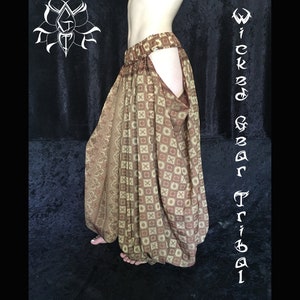 May include: Brown and tan tribal pants with a geometric and floral pattern. The pants have a wide waistband and a unique open-leg design. The words "Wicked Gear Tribal" are written vertically on the right side of the image.