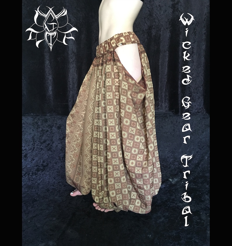 May include: Brown and tan tribal pants with a geometric and floral pattern. The pants have a wide waistband and a unique open-leg design. The words "Wicked Gear Tribal" are written vertically on the right side of the image.