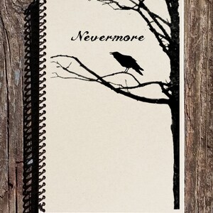 May include: A black and white spiral bound notebook with the word "Nevermore" written in cursive on the front cover. A silhouette of a raven perched on a bare tree branch is also on the cover.