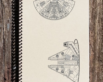 May include: A black and white line drawing of the Millennium Falcon spaceship on a beige notebook. The spaceship is shown from the top and the bottom.
