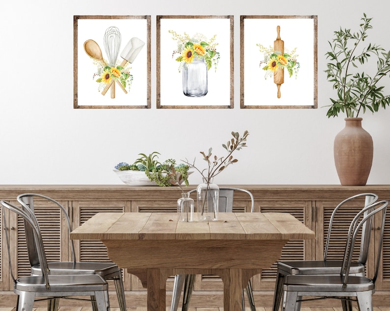 May include: Three framed watercolor prints with a kitchen theme. The prints feature a mason jar with sunflowers, a rolling pin with sunflowers, and a whisk, spatula, and wooden spoon with sunflowers.