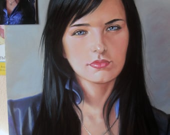 May include: A painting of a woman with long black hair wearing a blue shirt and a silver necklace with a pendant. The woman has blue eyes and is looking directly at the viewer.