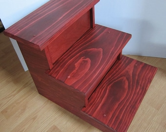 May include: Three-step wooden pet stairs in a rich mahogany stain. The stairs are made of solid wood and have a smooth finish.