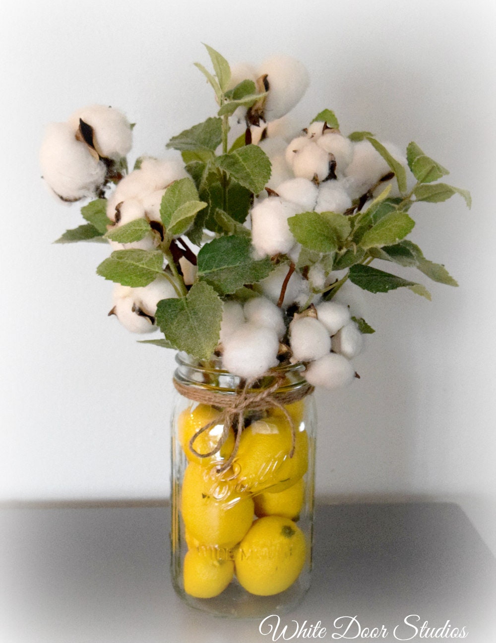 Cotton Stem And Greenery Arrangement In Lemon Filled Mason Jar