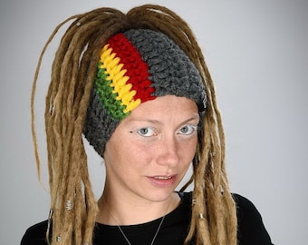 May include: A woman with long blonde dreadlocks is wearing a gray crocheted headband with a red, yellow, and green stripe. She is also wearing a black t-shirt and a silver necklace with a white oval pendant.