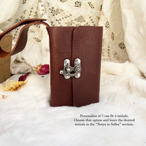 May include: A dark brown leather journal with a silver clasp closure and a matching leather handle. The journal is rectangular and appears to be handmade. The text on the image says, "Personalize it! I can fit 2 initials."
