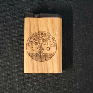 May include: A wooden box with a black lid, featuring a laser-engraved design of a tree of life with a moon, sun, and stars. The box has a natural wood grain finish.