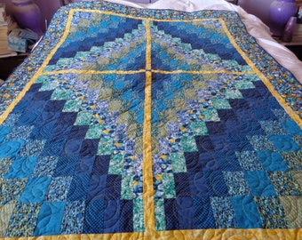 May include: A blue and yellow quilt with a geometric pattern. The quilt is made of squares and rectangles, and the pattern is symmetrical. The quilt is quilted with a floral design.