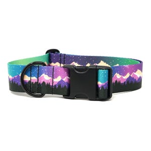 May include: A colorful dog collar featuring a mountain and starry night design. The collar has a black buckle and a black metal D-ring. The design includes shades of blue, purple, and green.