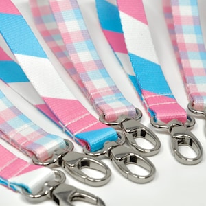 May include: Six colorful lanyards with silver swivel clips. The lanyards are pink, blue, and white with stripes and plaid patterns.