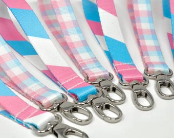 Peut inclure: Six lanyards colorés avec des clips pivotants argentés. Les lanyards sont roses, bleus et blancs avec des rayures et des motifs à carreaux.