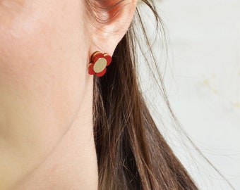 May include: A pair of red flower-shaped stud earrings with a gold center.