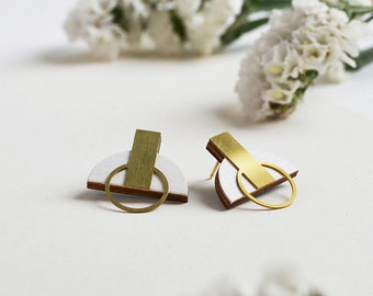 May include: A pair of white and gold geometric earrings. The earrings are made of wood and metal and have a simple, modern design.