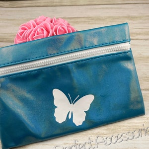 May include: Teal-colored zippered pouch with a white butterfly design. The pouch has a white zipper and is made of a shiny material. The words "Jenns Perfect Accessories" are printed on the bottom right.