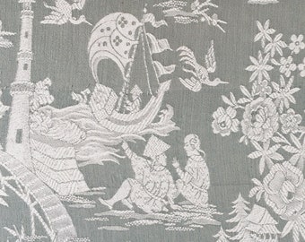 Puede incluir: Una tela con estampado blanco y gris con un diseño repetido de un paisaje chino. La tela presenta un puente, una pagoda, un barco, un caballo y un jinete. El fondo es de color gris claro.