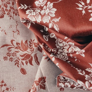 May include: Two pieces of fabric with a floral pattern. One piece is a dark red colour with white flowers and the other is a light grey colour with red flowers.