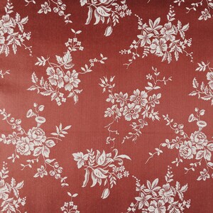 May include: A red fabric with a white floral pattern. The fabric has a subtle sheen and a textured surface.