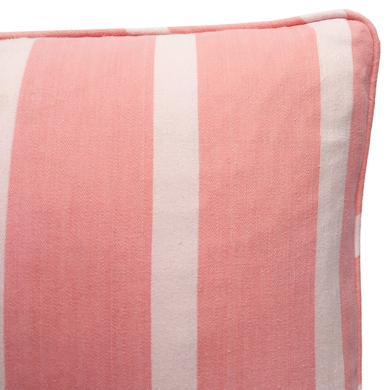 May include: A pink and white striped cushion with a subtle herringbone pattern. The cushion has white piping around the edges.
