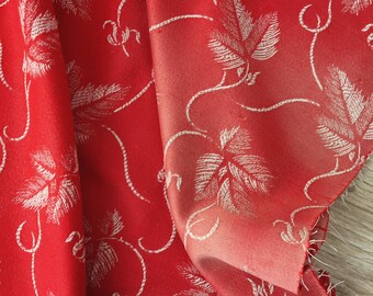 Könnte beinhalten: Roter Stoff mit einem weißen Blumenmuster. Der Stoff ist gefaltet und hat eine weiche, seidenartige Textur.
