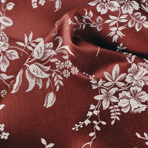 May include: Burgundy fabric with a white floral pattern. The fabric is textured and has a subtle sheen.