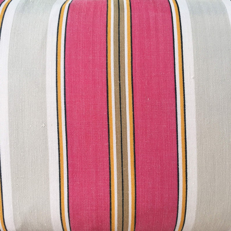 May include: Striped fabric with alternating bands of pink, white, yellow, and brown. The fabric has a subtle texture.
