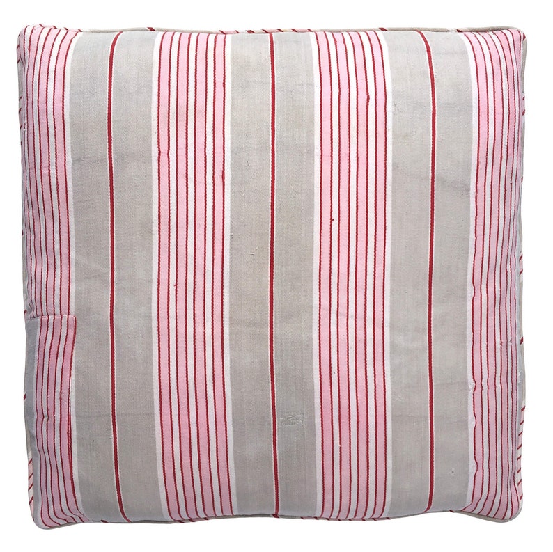 May include: A grey and white striped pillow with pink and red stripes. The pillow is made of a soft, woven fabric.