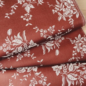 May include: Red fabric with a white floral pattern. The fabric is folded in thirds, showing the pattern from different angles.