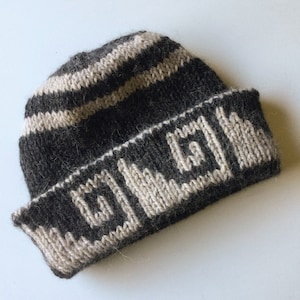 Puede incluir: Un gorro de punto de rayas blancas y negras con un patrón geométrico en el borde.