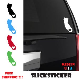 May include: A white decal of the state of California with a small red heart in the center. The decal is on the back window of a black car. The text "MADE IN U.S.A" and "SLICKSTICKER" are visible below the decal.