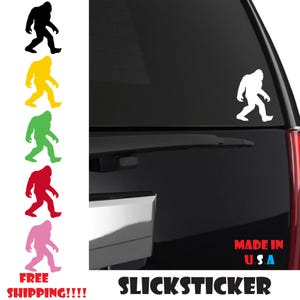 May include: A white silhouette of Bigfoot walking, with the words "Slicksticker" and "Made in U.S.A." below. The image also shows a variety of color options for the sticker, including black, yellow, green, red, and pink.