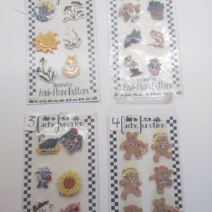 May include: Four cards with the text "Cache Junction" and "Handcrafted Semi-Stone Buttons". Each card features a set of six colorful, hand-painted, semi-stone buttons with various themes, including a sun, a moon, a flower, a bird, a bear, and a house.