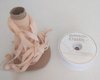 May include: A spool of pale pink elastic trim with a white label that reads "Stretch Trim Elastic" on a white surface.