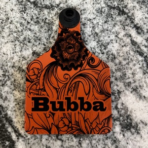 May include: Orange plastic tag with a black floral design and the word "Bubba" in black lettering.