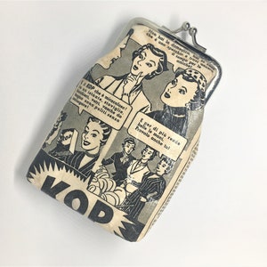 May include: A vintage-style coin purse with a black and white comic book design featuring women and text in Italian. The purse is made of a cream-colored fabric with a silver metal clasp.