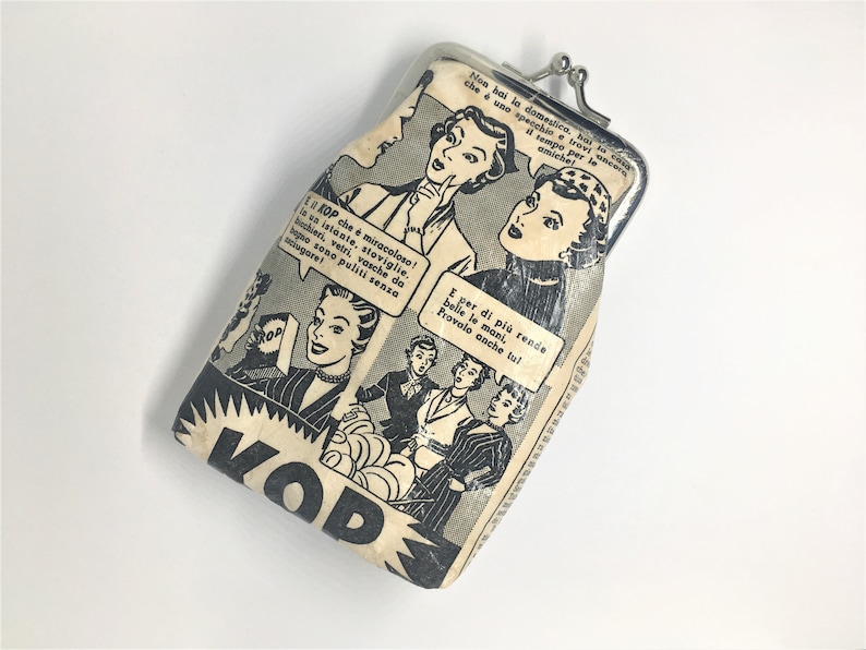 May include: A vintage-style coin purse with a black and white comic book design featuring women and text in Italian. The purse is made of a cream-colored fabric with a silver metal clasp.