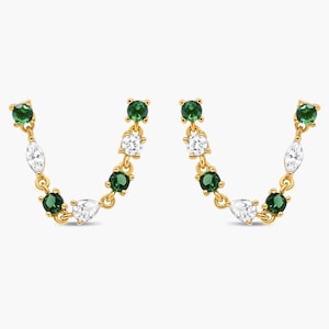 May include: A pair of gold chain earrings featuring a U-shaped design. Each earring is adorned with alternating round-cut green stones, marquise-cut clear stones, and a single pear-cut clear stone, all set in a polished gold metal link chain.