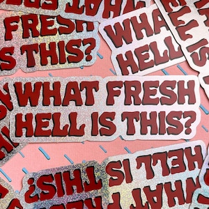 May include: A set of silver holographic stickers with red text that reads "What Fresh Hell Is This?" The stickers are glittery and have a fun, sarcastic tone.