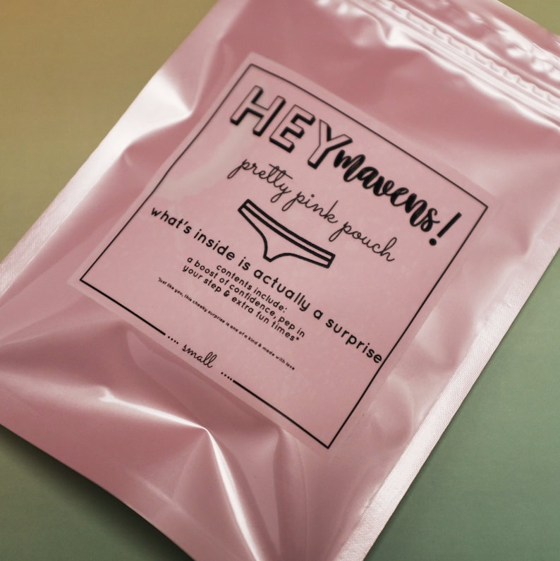 May include: A pink pouch with a white label that says "HEYmavens! pretty pink pouch what's inside is actually a surprise contents include: a boost of confidence, pep in your step & extra fun times" and "..... small"