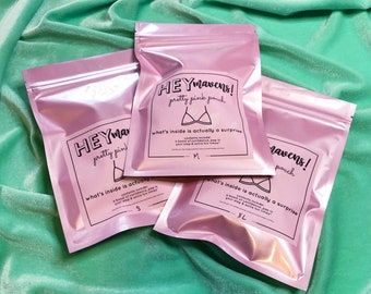 May include: Three pink zippered pouches with the text "HEYmavens! pretty pink pouch" and "what's inside is actually a surprise". The pouches are labeled with sizes S, M, and XL.